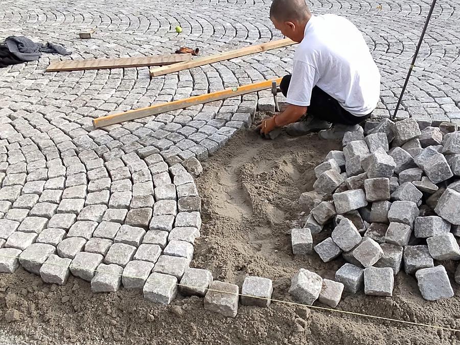 Paveur posant des pavés gris en éventail